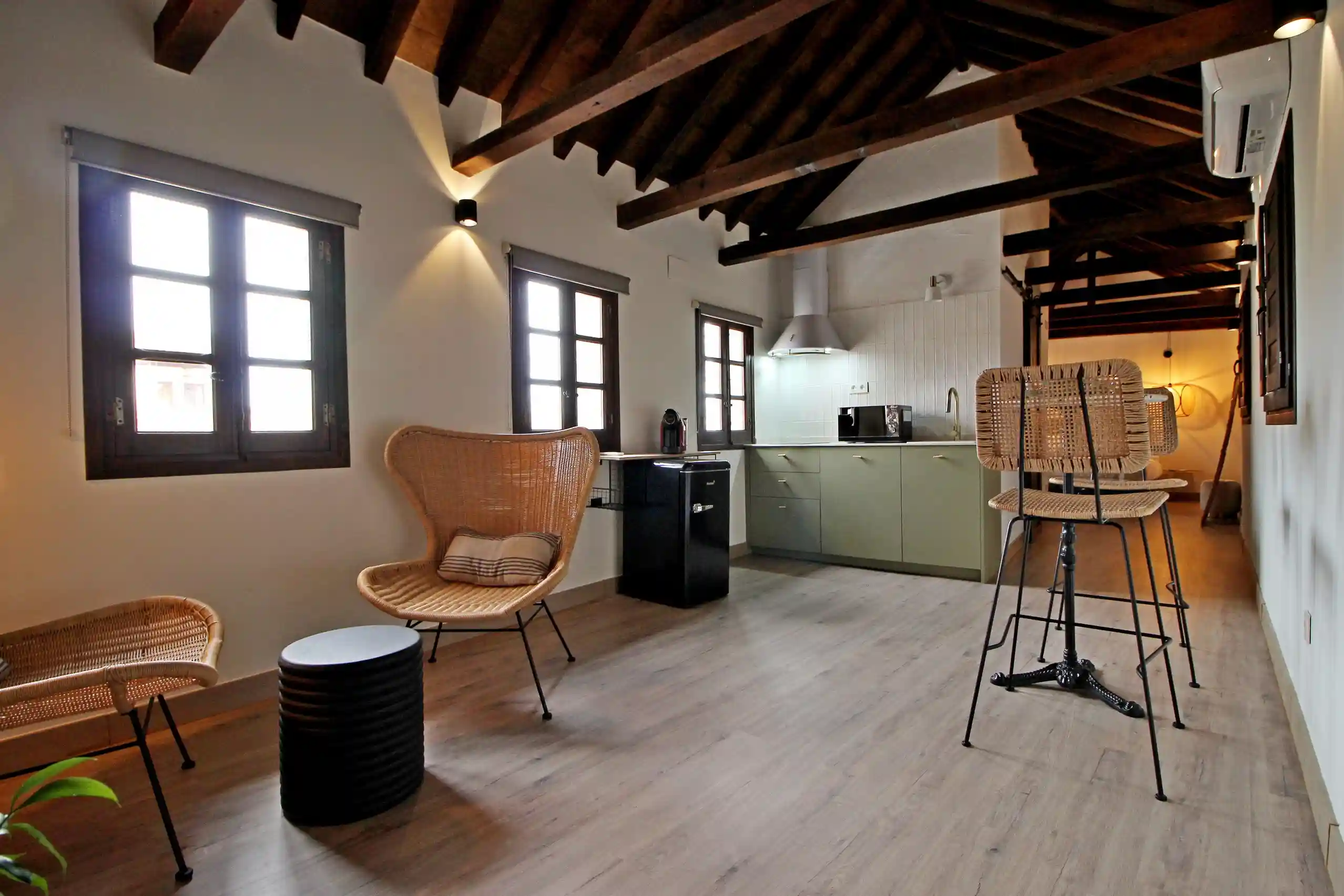 Salón con vigas de madera y cocina equipada en apartamento turístico El Patio de los Ángeles en el centro histórico de Toledo.